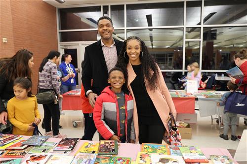 A man, woman and child by a table of books