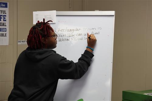 A student writes on a white board.