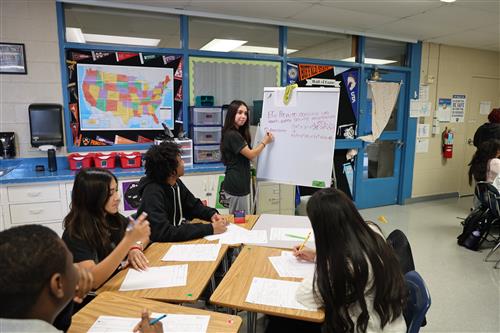 A student does a math equation on the white board