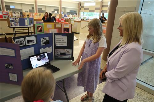 A woman looks a female student explaining her research