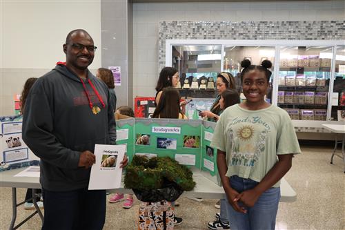 a father and daughter stand in front of a research project