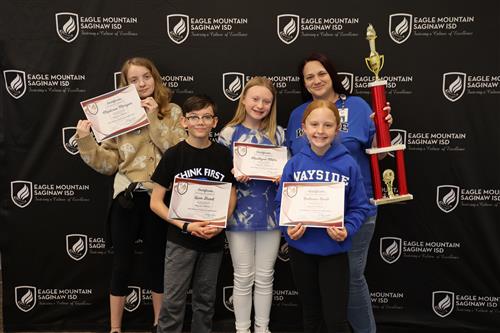 five students holding certificates and a trophy