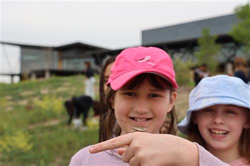 a girl holds up a grasshopper