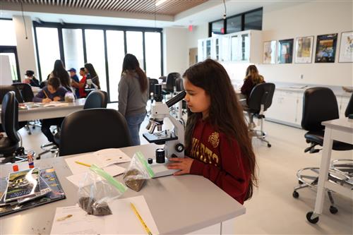 A girl looks through a microscope