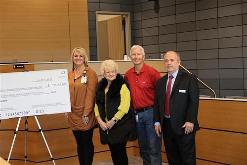 four adults standing next to a large ceremonial check
