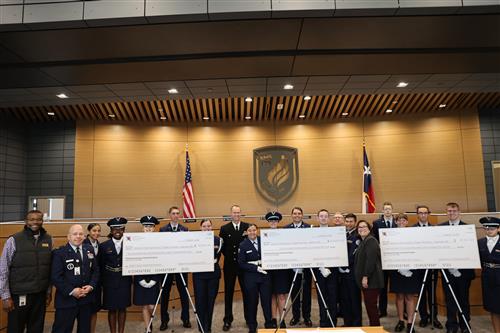 Students and officials with three large ceremonial checks