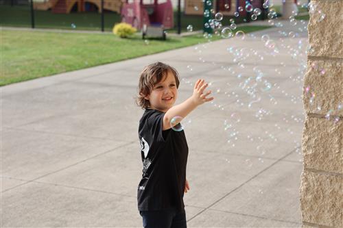 A boy reaches out to touch bubbles