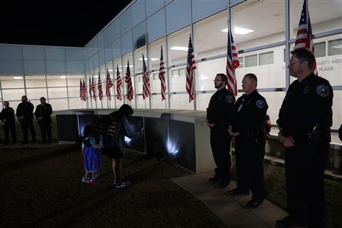 Police Officers stand guard. A family looks at the wall.