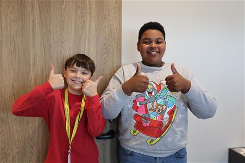 Two boys holding their thumbs up