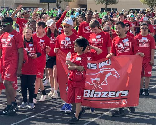 athletes walk into an area with a banner
