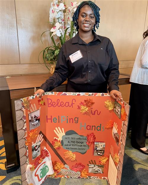 A girl in professional dress holding a bulletin board