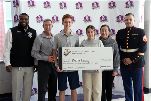 Family standing together with one member in marine corps uniform holding large symbolic check