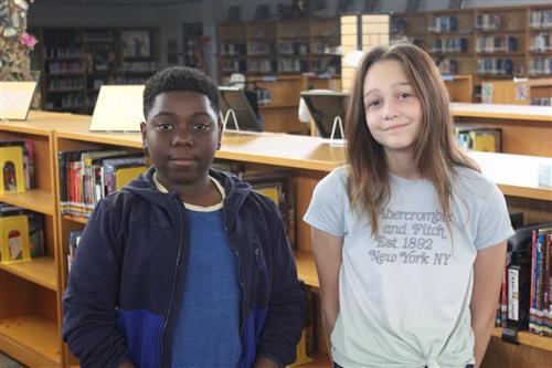 A boy and girl standing next to each other in the library
