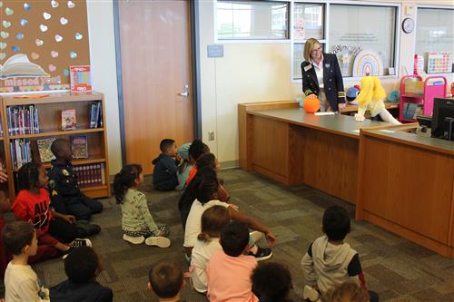 A woman and a puppet talk to students