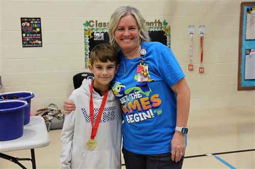 A woman stands next to a boy with a medal