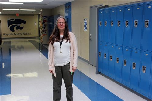 A woman stands in a school hallway