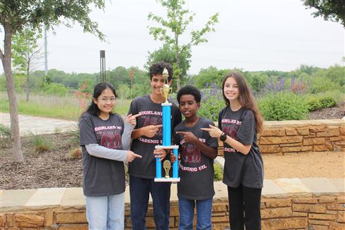 A group of students outside holding a trophy