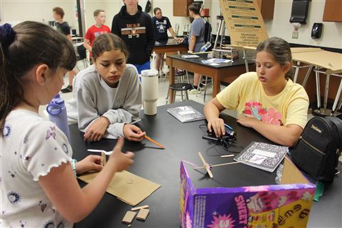 three middle school age girls work on a science project
