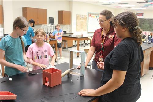 three girls and an adult female work on science project