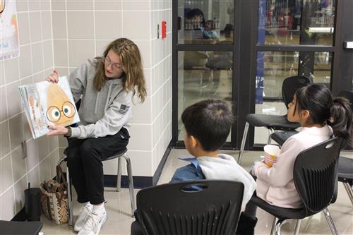 Older student reading to younger students