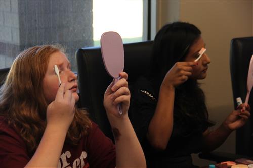Students apply makeup with tooth brushes