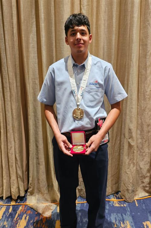 High school student in a blue shirt wearing and holding a medal