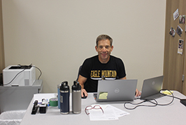  a man sits at a desk and smiles