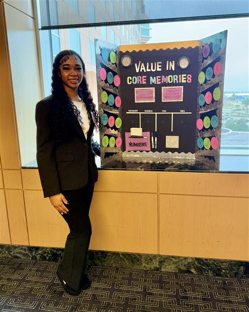 A girl in professional dress next to a bulletin board