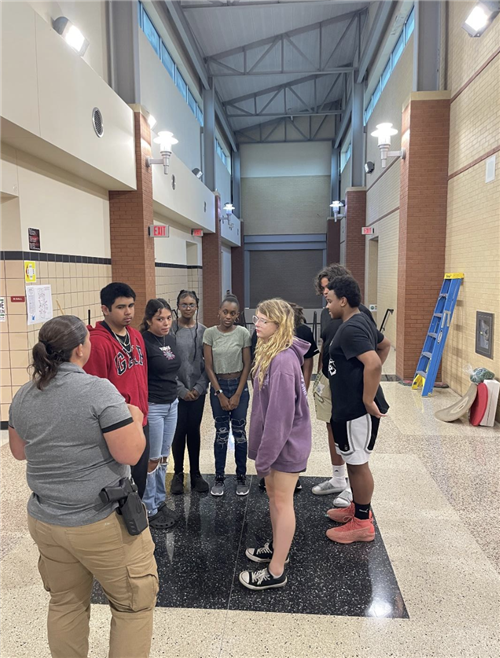 Students listen to a police officer speak