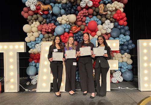 A group of girls in professional dress with certificates