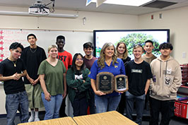  A teacher holding two plaques with students standing around her