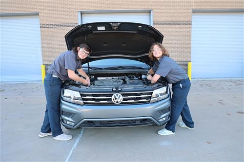 Two students under the hood of a car