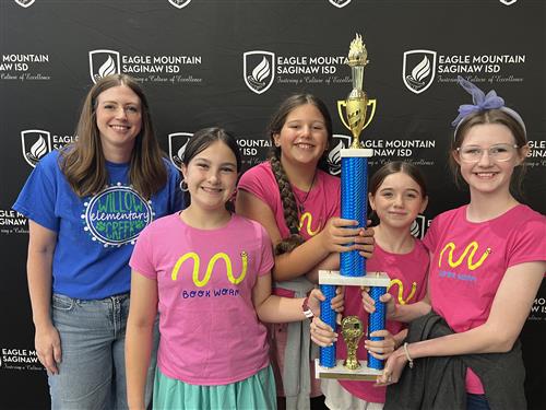 A goup of students hold a trophy while their teacher stands next to them