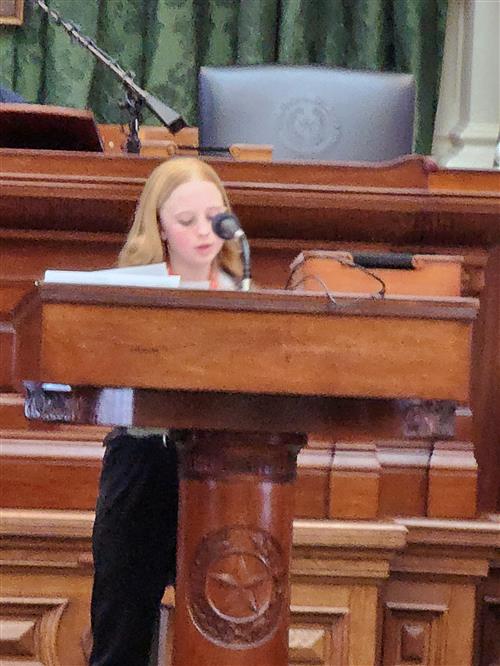 A girl stands behind a podium