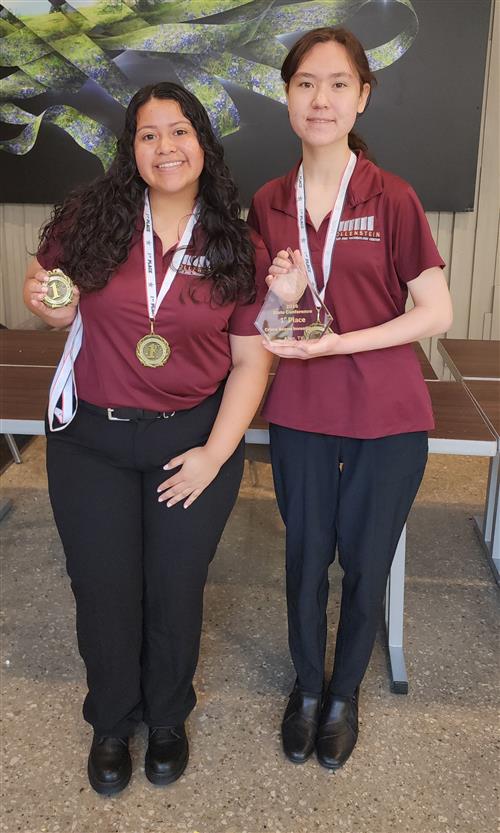 Two girls hold medals and awards