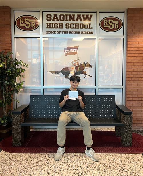 A boy sitting down holding a card