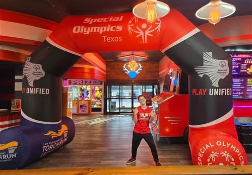 A student stands under a special olympics blow up tunnel