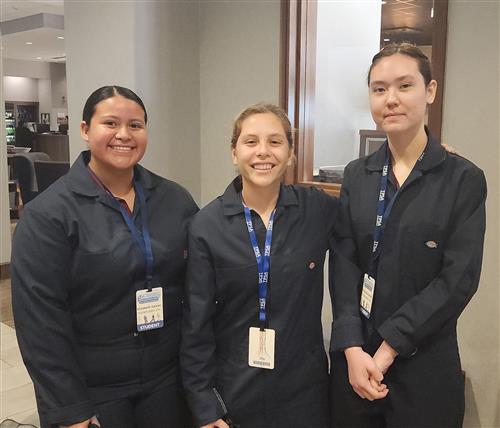 Three girls in crime scene investigation uniforms stand together
