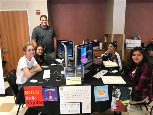 Animation and graphic arts students pose at their booth. 