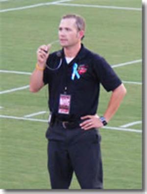Matt Pearson, director bands, speaking into a microphone on the football field 