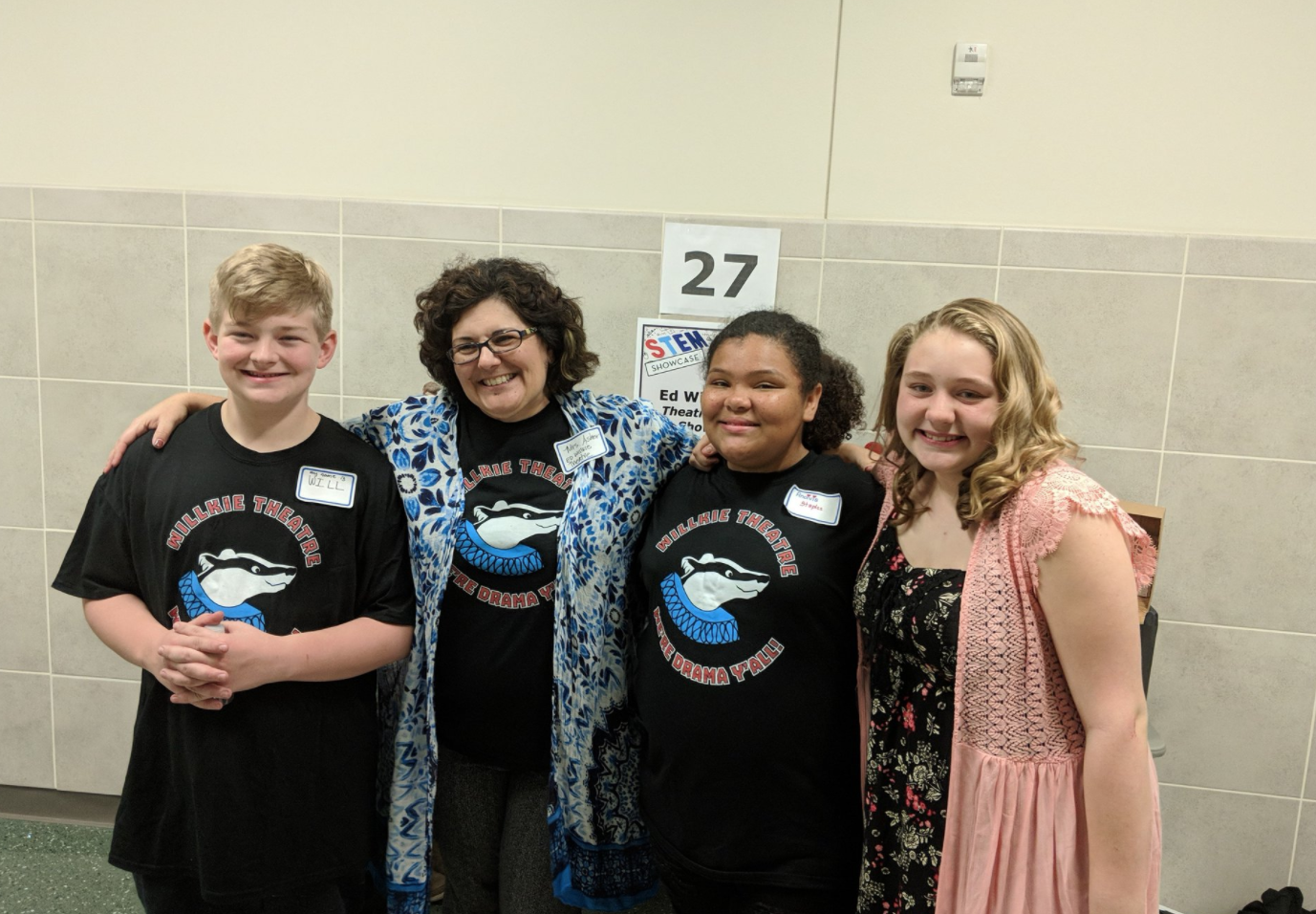 Three theatre students and teacher smile for a photo