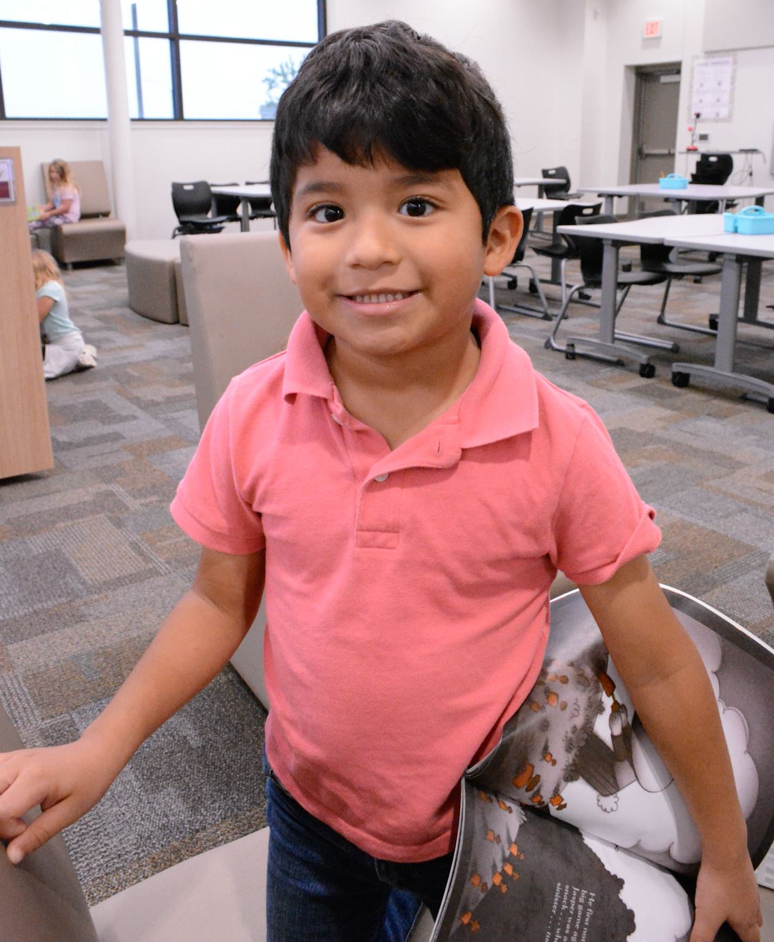 student holds a book and smiles in a library