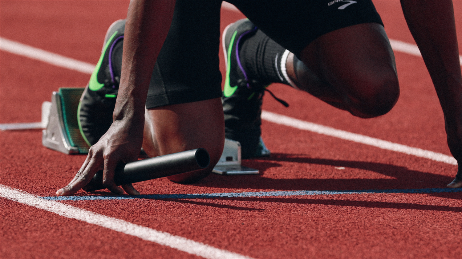 runner in the blocks holding a relay stick